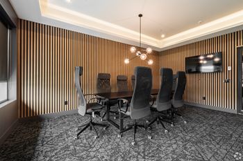 A conference room with a wooden panelled wall and a television.